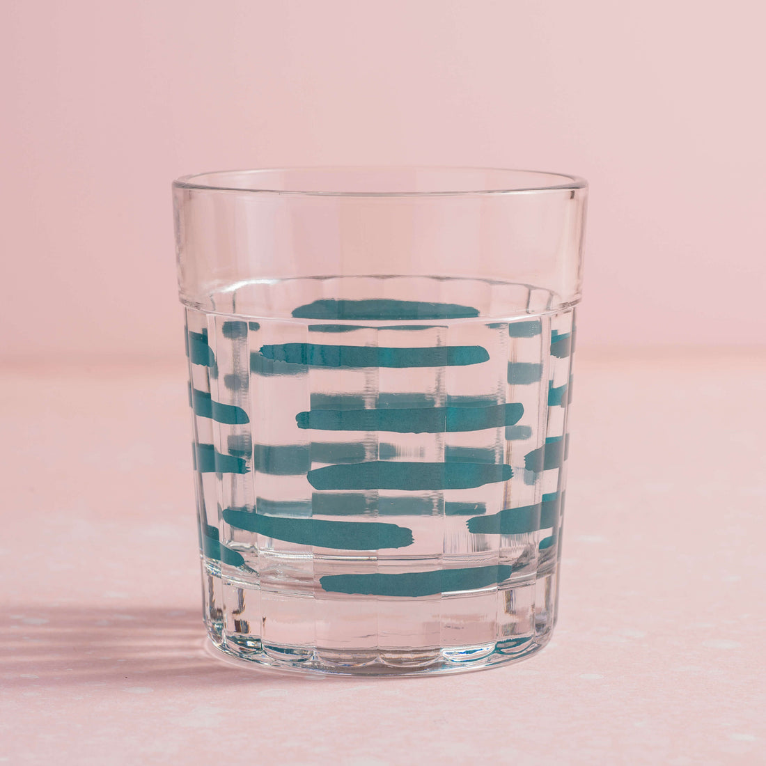 copo artista com estampa de tracinhos verdes sobre fundo rosa claro