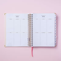 planejamento anual do Do Planner 2024 equilibrista meg & meg sobre fundo rosa claro