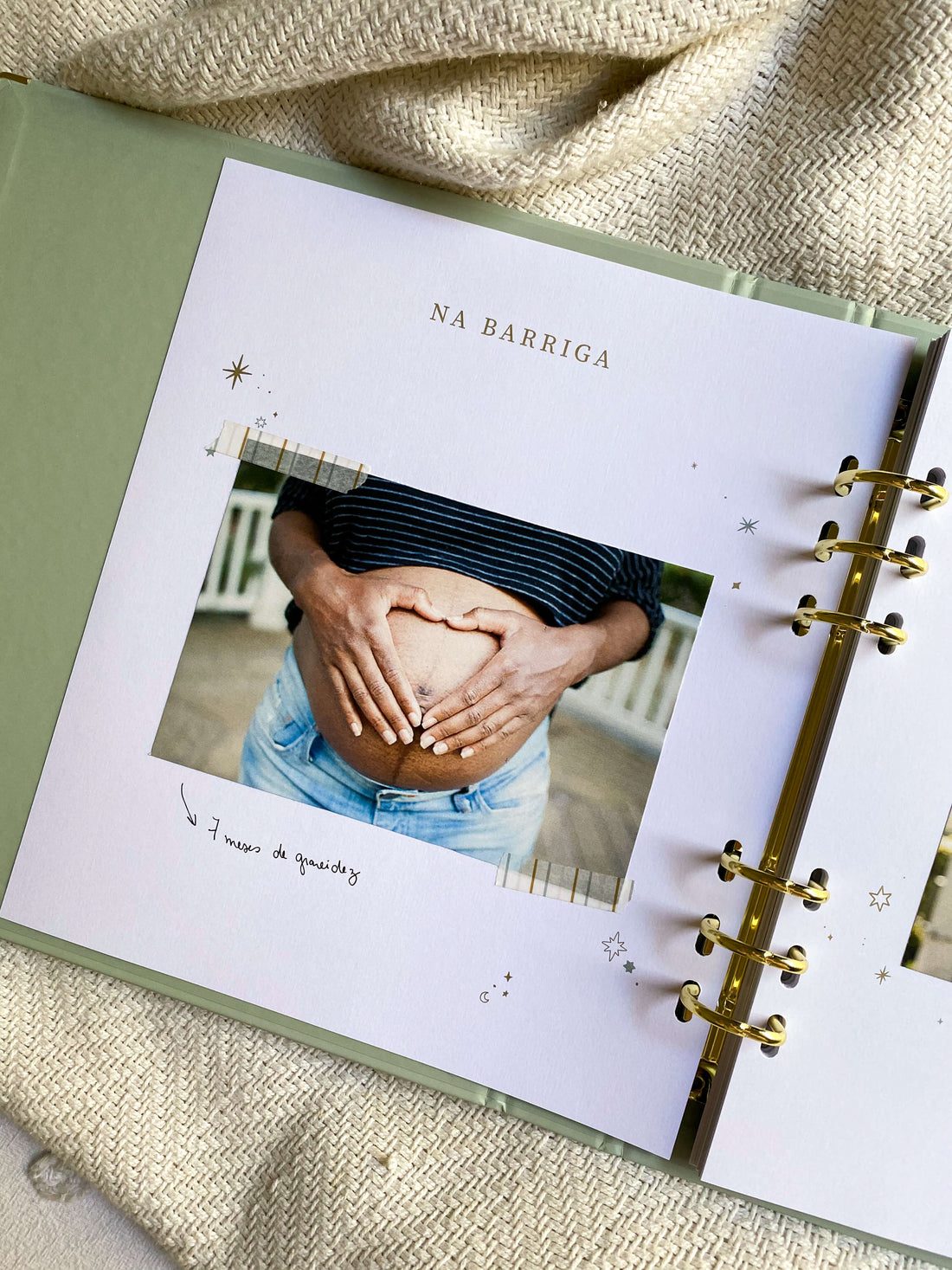 livro do bebê sobre cama com foto de barriga de mulher grávida colada