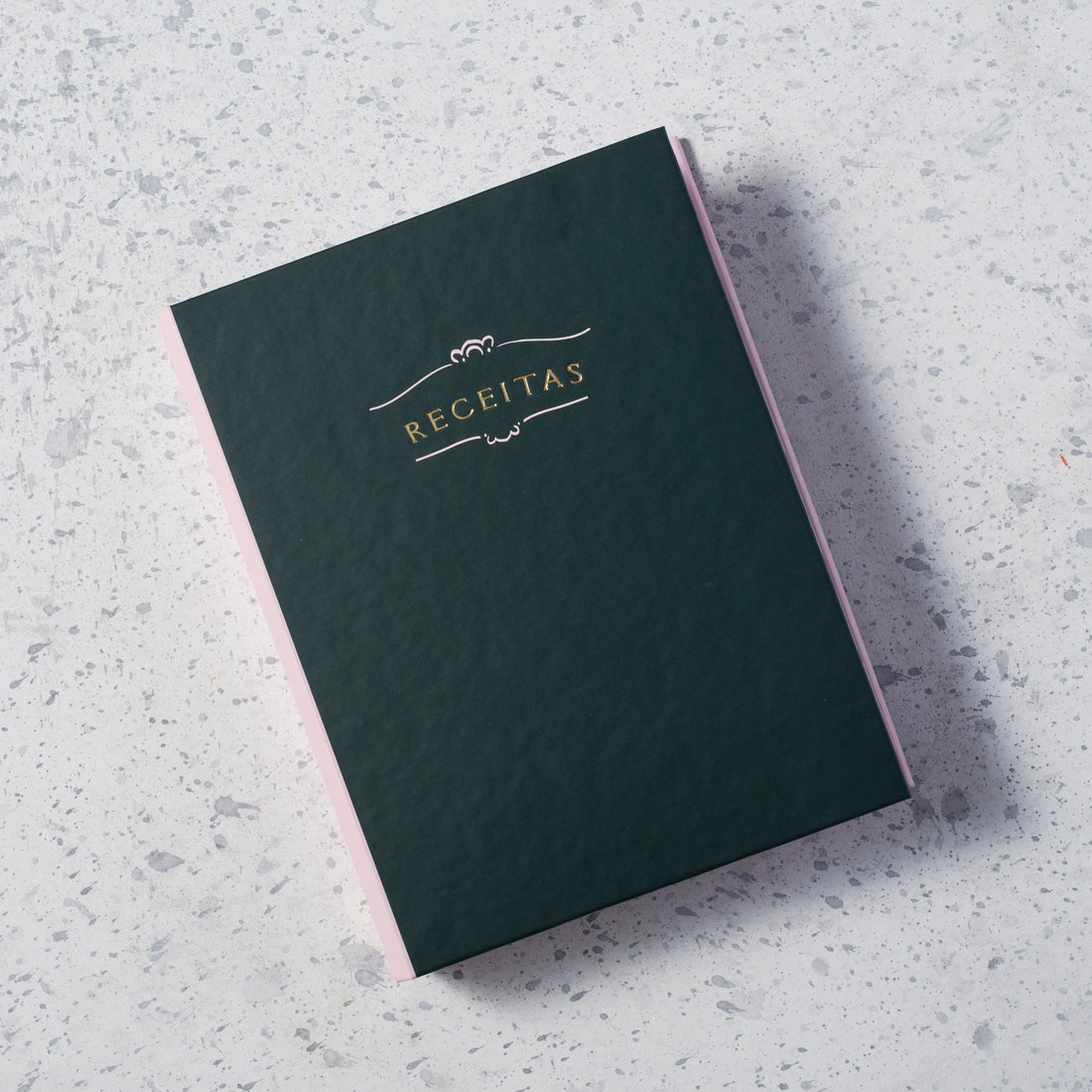 caderno de receitas verde escuro com hot stamp dourado sobre fundo marmorizado
